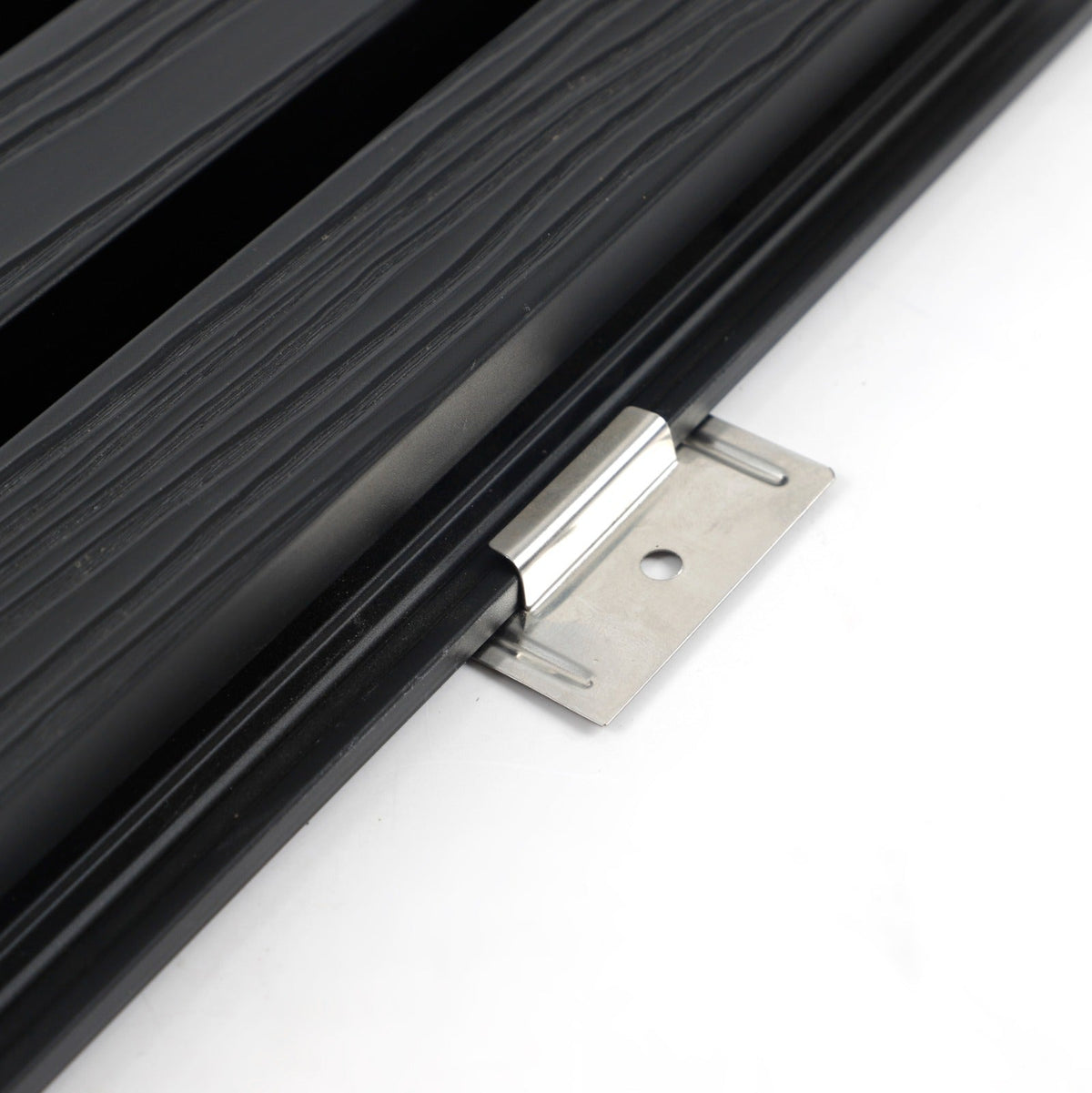 Close-up of stainless steel installation bracket clipped beneath the edge of black composite cladding