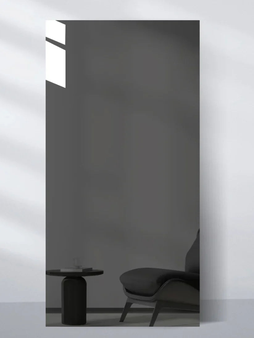 Gray mirror-finish wall panel sample reflecting a minimalist chair and round side table