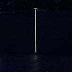 Vertical LED fence post light illuminating composite privacy fence at night