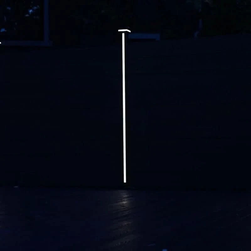 Vertical LED fence post light illuminating composite privacy fence at night