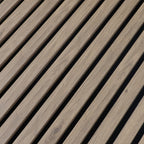 Close-up of the white wood veneer grain and evenly spaced black gaps between acoustic slats