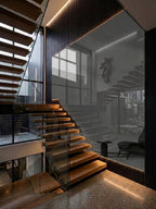 Floor-to-ceiling gray mirror panel installed beside a floating wood staircase with black slatted trim