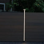 Vertical LED fence post light installed between composite privacy fence panels at night