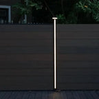 Vertical LED fence post light mounted on composite privacy fence for outdoor night illumination