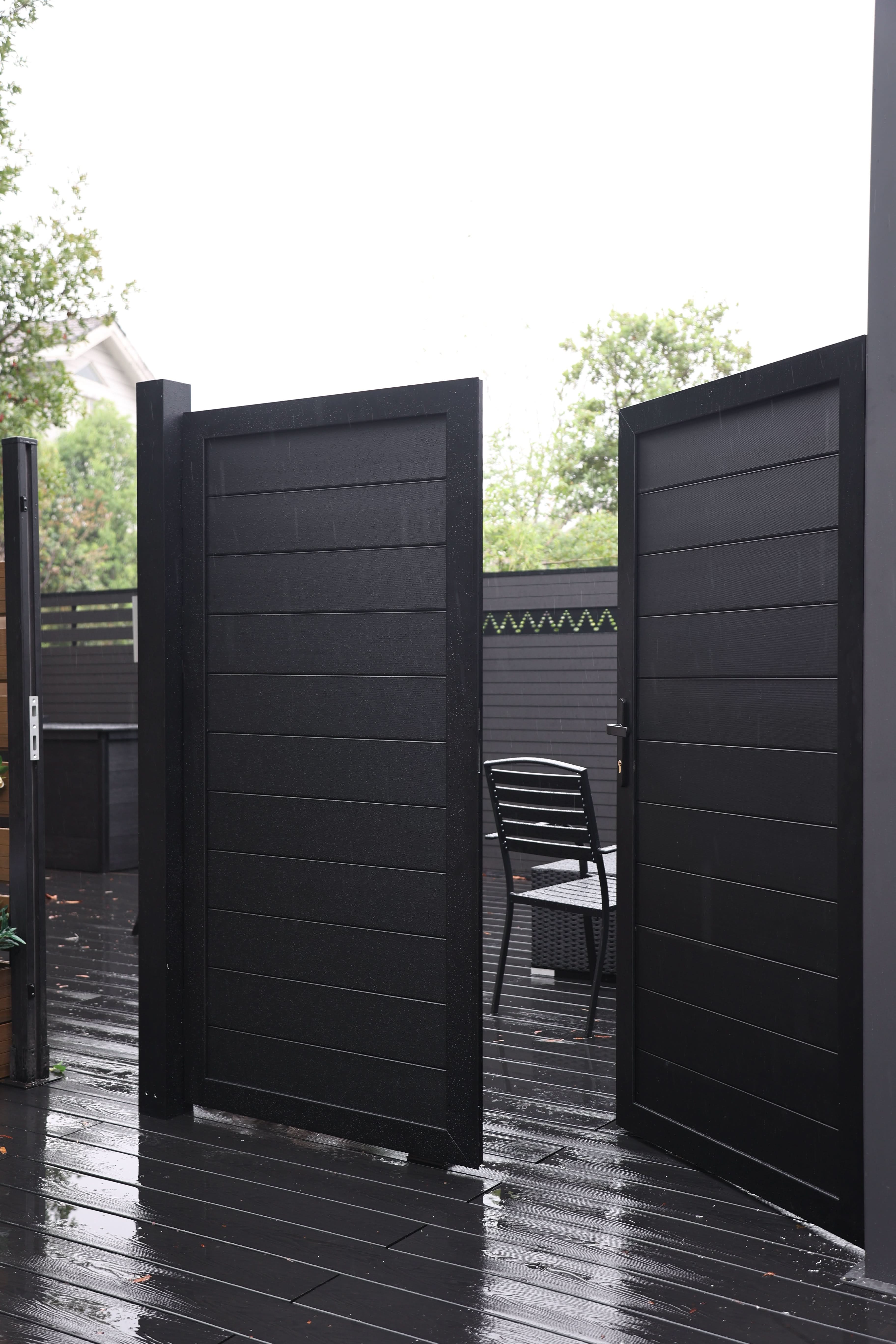 Black aluminum double privacy fence gate with horizontal slat panels in modern outdoor space