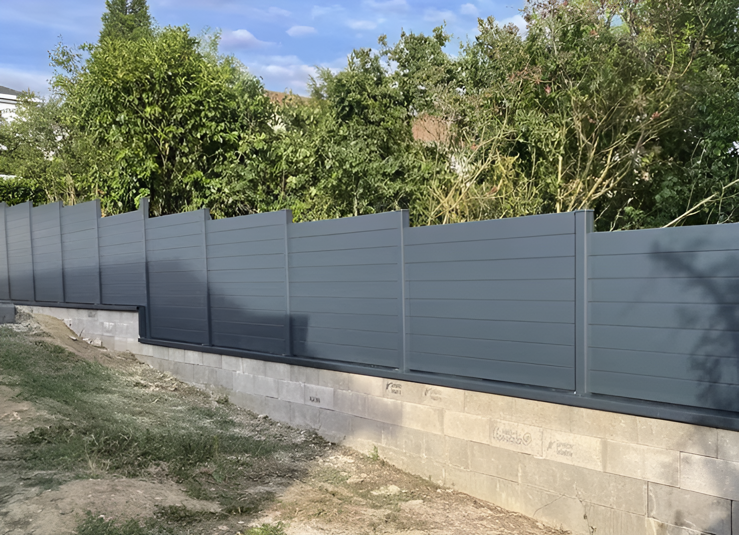 Light gray composite privacy fence with horizontal panels installed on concrete base