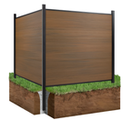Corner view of wood-grain composite privacy fence with black aluminum posts installed in ground