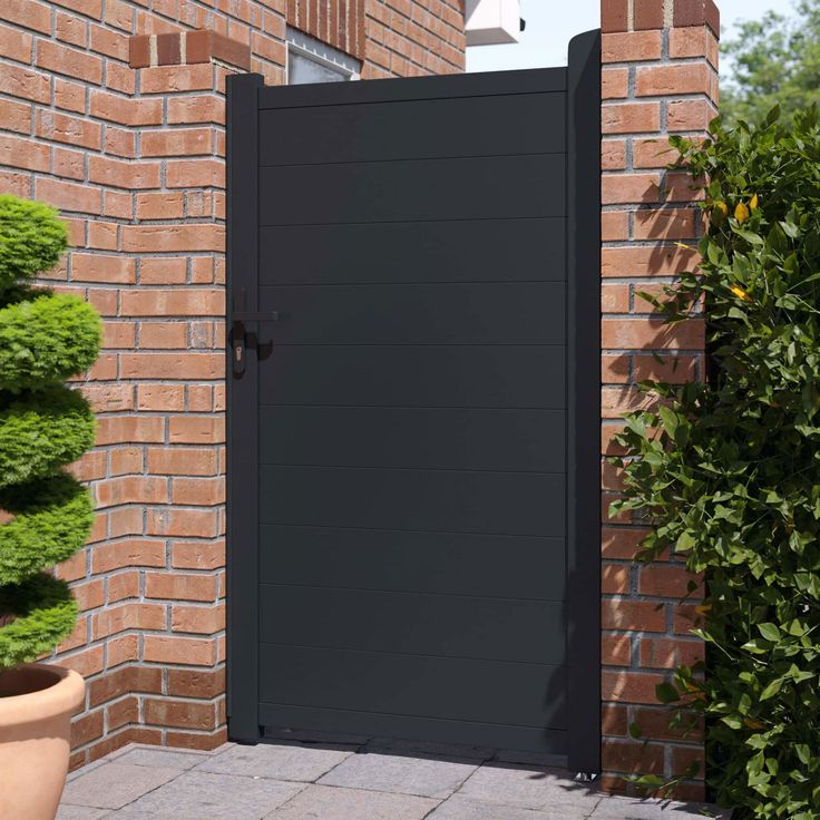 Black composite single fence gate with aluminum frame installed between brick pillars