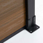Bottom detail of wood-grain composite fence panel with black aluminum post base