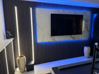 Modern TV feature wall with fluted panels, recessed vertical LED strip lighting, and marble accent surround