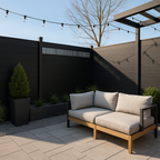 Black composite privacy fence with slotted top panel installed in modern patio seating area with pergola and string lights