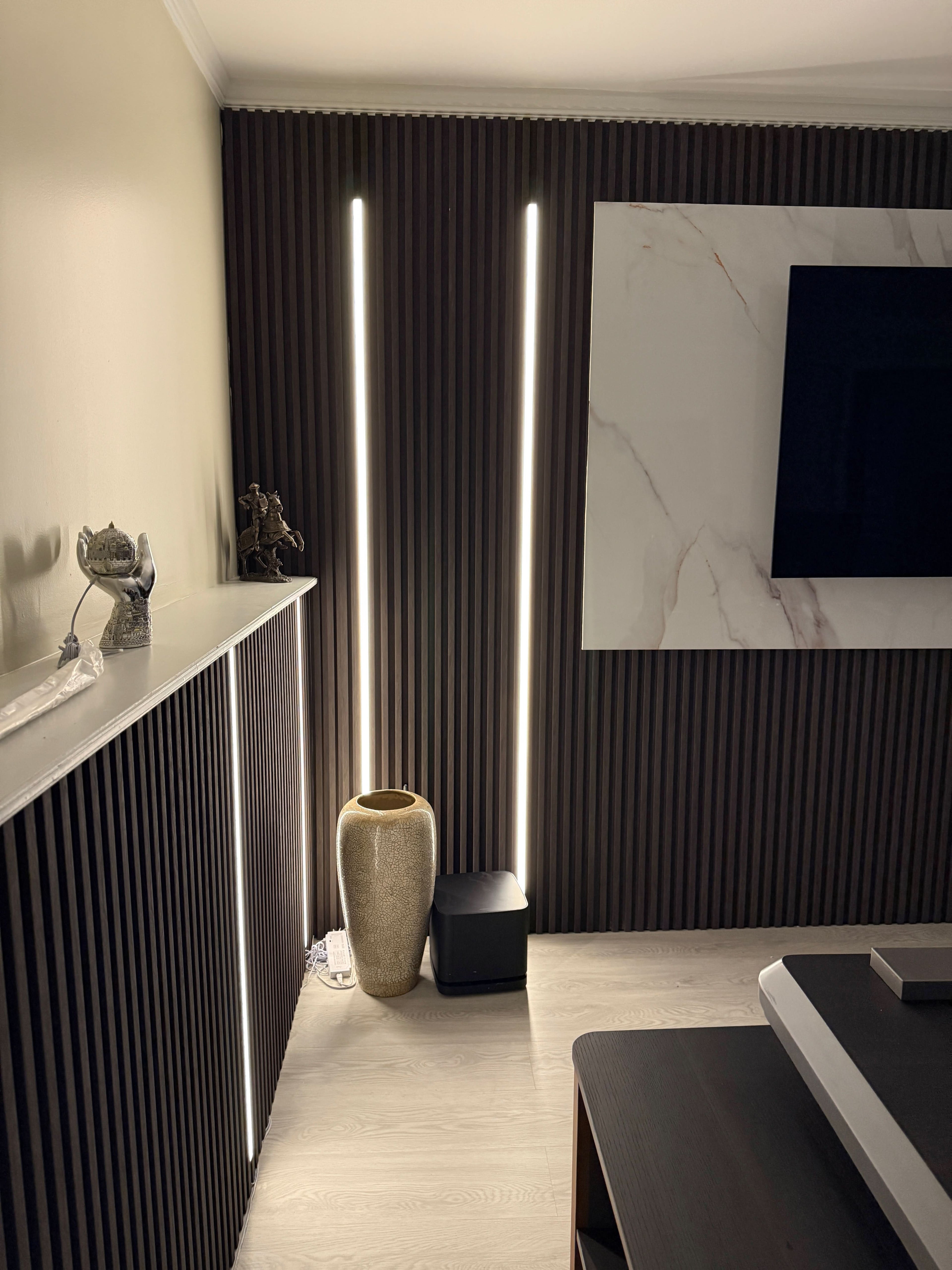 Vertical recessed LED strip lighting on fluted wall panels for modern TV feature wall