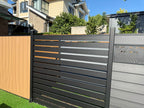 Mixed gray and black composite horizontal slat fence panel installed in residential backyard