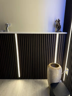 Vertical recessed LED strip lighting integrated into fluted wall panels for modern interior accent lighting