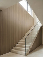Royal Oak wood veneer panels covering a tall stairwell wall beside a white staircase and glass railing