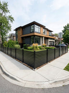 Black open slat aluminum fence panels installed around a landscaped corner property