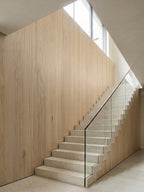 White oak veneer panels installed along a tall stairway wall with glass railing