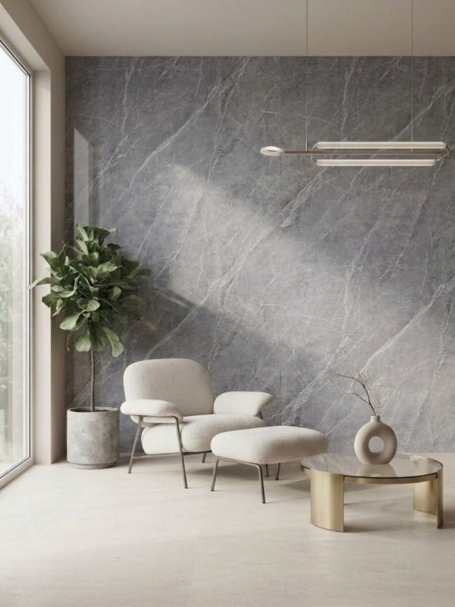 Ash gray marble PVC wall panel behind a cream lounge chair, ottoman, plant, and round coffee table