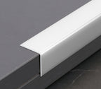 Silver-white aluminum L cap trim covering the edge of a dark wall panel